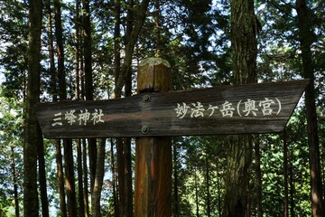 The road sign near Mitsumine Jinja Shrine Okumiya at Myohogatake mountain in Chichibu, Tokyo, Japan. Japanese text:Right"Myohogatake mountain (Okumiya((Rear shrine))) ".   Left:"Mitsumine Jinja Shrine