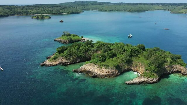 Drone shot of a beautiful tropical island near Lombok, Indonesia. Camera tilts slightly up, drone moving down and backwards, revealing more of the gorgeous scenery of the seascape.