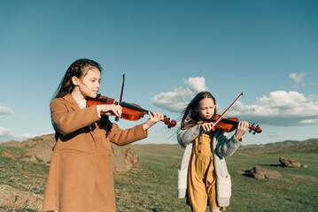 two little girls with violins outside in the sunset