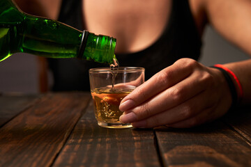 Woman at a bar pouring alcohol into a shot glass.