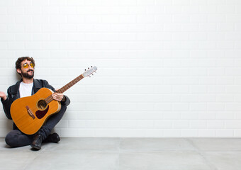 young cool man playing guitar sitting on the floor