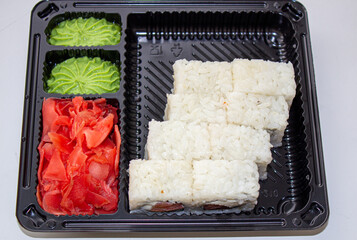 Sushi box. Japan menu in black transport box or bento box on gray background, top view, close up, from above