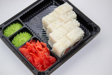 Sushi box. Japan menu in black transport box or bento box on gray background, top view, close up, from above