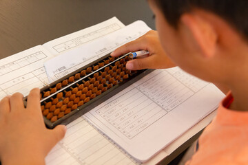 Boy practicing abacus (Japanese traditional calculation tool which strengthen mind calculation) - obrazy, fototapety, plakaty