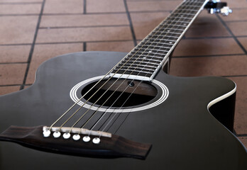 Fototapeta premium Black acoustic guitar on the brick floor. Closeup top-down photo.