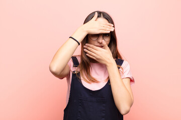 young pretty woman covering face with both hands saying no to the camera! refusing pictures or...