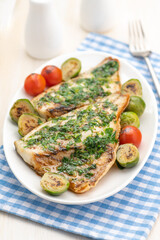 Baked White Fish Fillet with vegetable garnish and butter and lemon.
