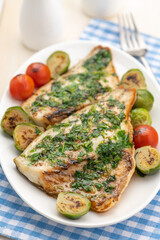 Baked White Fish Fillet with vegetable garnish and butter and lemon.