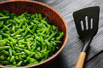 Vegetarian food. Fried string beans in a pan. Stylish background for design. Minimalism. Healthy food from vegetables.