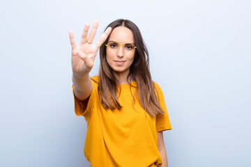 young pretty woman smiling and looking friendly, showing number four or fourth with hand forward,...