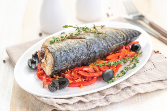 Baked fish mackerel with vegetables, sweet pepper and black olives and herbs.