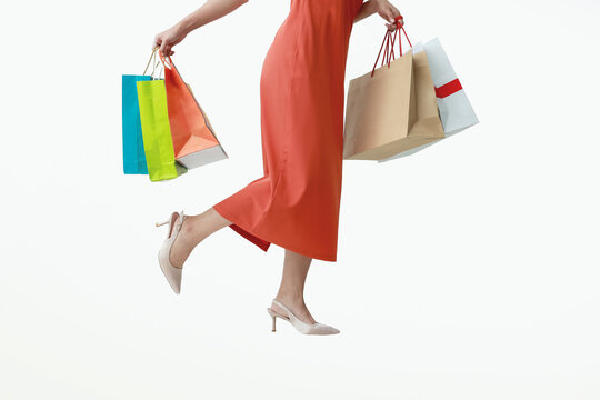 Woman of half body in red pants holding multicolored shopping bags isolated white background.
