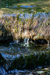 Klares Wasser einer sprudelnden Quelle mit sauberem Wasserfall und Bach mit seidigen Wellen für Entspannung und Meditation zeigen schöne Reflexionen auf der Wasseroberfläche mit unberührter Natur