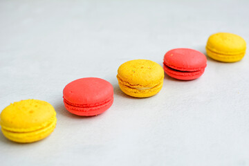 Obraz na płótnie Canvas Red and yellow macaroons in a line on a white background.