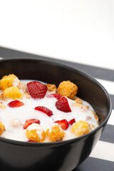 Mueslis with berries in a black  cup on the table, macro