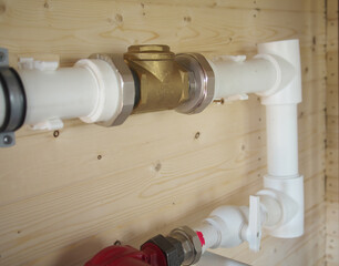 mounting of gravity heating system equipment with laser level in a boiler room. Circulation pump, stopcock, return valve, polypropylene tube and laser level