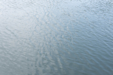 Water ripple surface reflection effect from sunset and sky top view at lake in evening day,wave abstract texture sunlight blue  pattern background