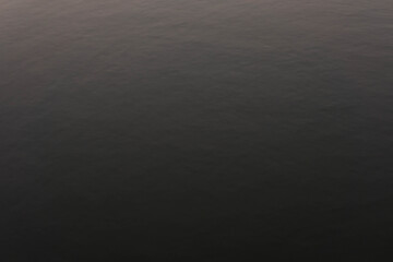 Water ripple surface reflection effect from sunset and sky top view at lake in evening day,wave abstract texture sunlight  pattern black background