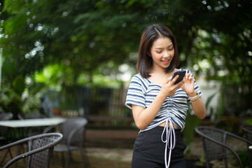 Young woman holding a smart phone on a city street.