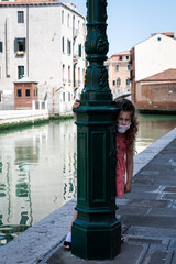little girl hiding behind an streetlight pole