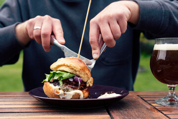 Man eating a homemade sandwich for lunch in a garde in summer time. Burger for healthy food with...