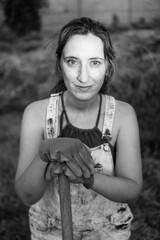 Black and white portrait of a woman working in the field with gloves on her hands. The peasant girl...