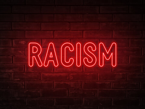 Racism - red neon light word on brick wall background
