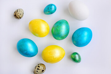 Chicken and quail eggs and Easter multi-colored painted eggs on a white background. View from above
