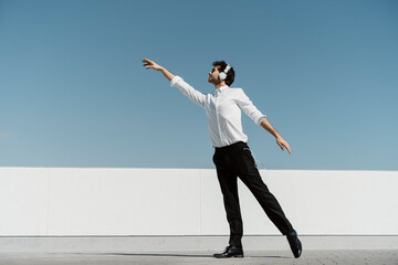 Ballet dancer with headphones practising on roof terrace