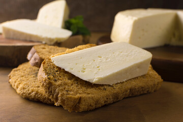 A Slice  of semi cured Brazilian Canastra chesse on a toast in wood background