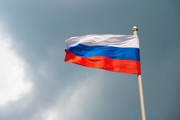 Fototapeta na wymiar Russian flag waving on a flagpole against a blue sky