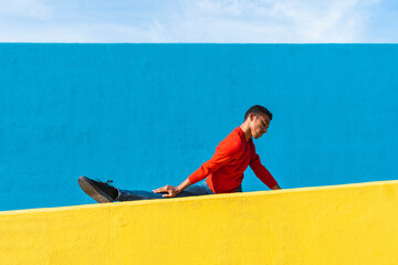 Young dancer stretching on yellow wall