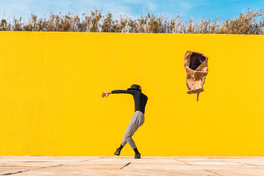 Young man dancing in front of yellow wall