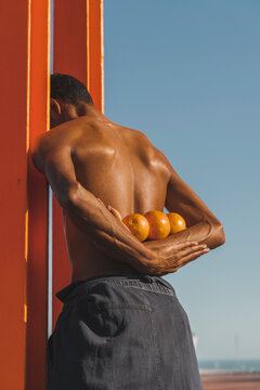 Rear view of man holding oranges while standing outdoors