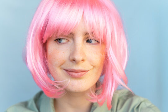 Portrait of young woman wearing pink wig glancing sideways