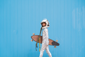 Kid dressed as an astronaut with longboard
