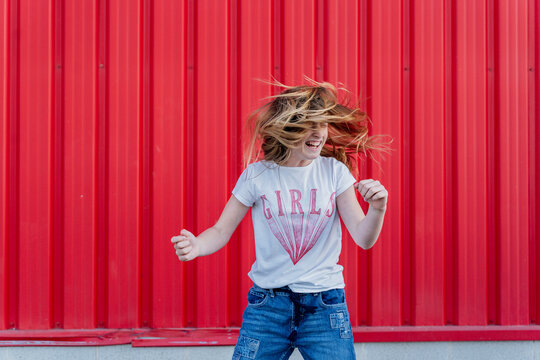 Girl headbanging in front of red wall