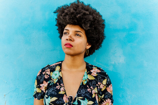 Portrait of Afro-American woman looking sideways, blue wall in the background