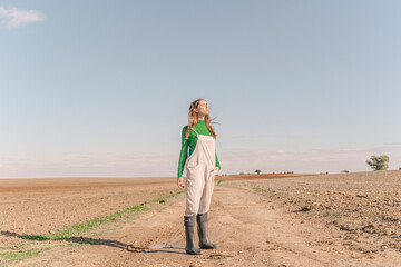 Young woman standing on dry field, with eyes closed