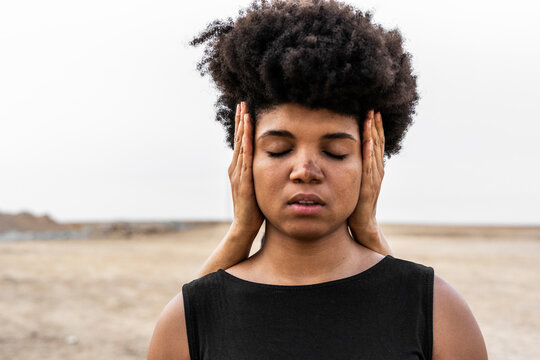 Woman's hands covering ears of another woman with eyes closed