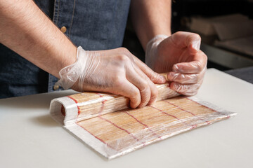 Sushi chef rolls the roll using a Mat