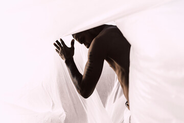 Barechested young man inside a plastic foil