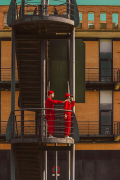 Young couple wearing red overalls and hats standing on platform looking at distance