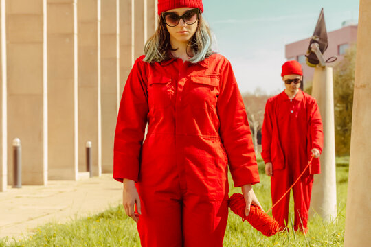 Young couple wearing red overalls and hats standing in a row connected with red string