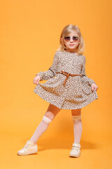 funny girl in leopard dress and glasses on yellow background posing
