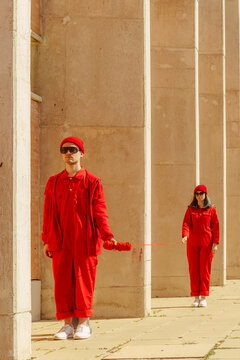 Young couple wearing red overalls and hats standing in a row connected with red string