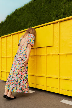 Desperate woman leaning head on yellow container in the street