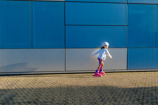 Little girl with safety helmet inline skating at sunlight