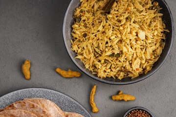 Kichari in a gray plate on a concrete surface next to condiments and tortillas top view