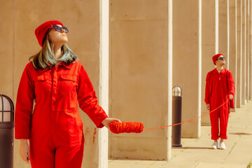 Young couple wearing red overalls and hats standing in a row connected with red string